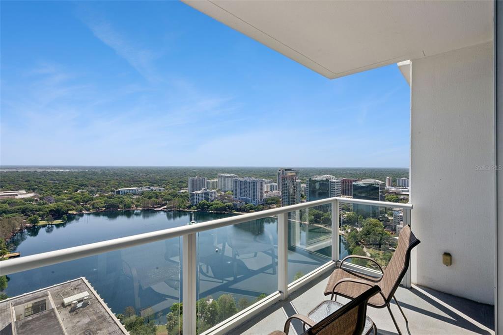 A high-rise balcony with glass railings overlooks a lake and a city skyline — 150 E ROBINSON STREET UNIT 2709, ORLANDO, FL