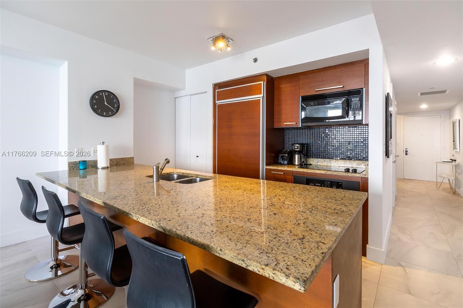 A kitchen features a granite island, dark wood cabinetry, and black bar stools — 1830 S OCEAN DR # 4705, Hallandale Beach FL 33009, HALLANDALE BEACH, FL