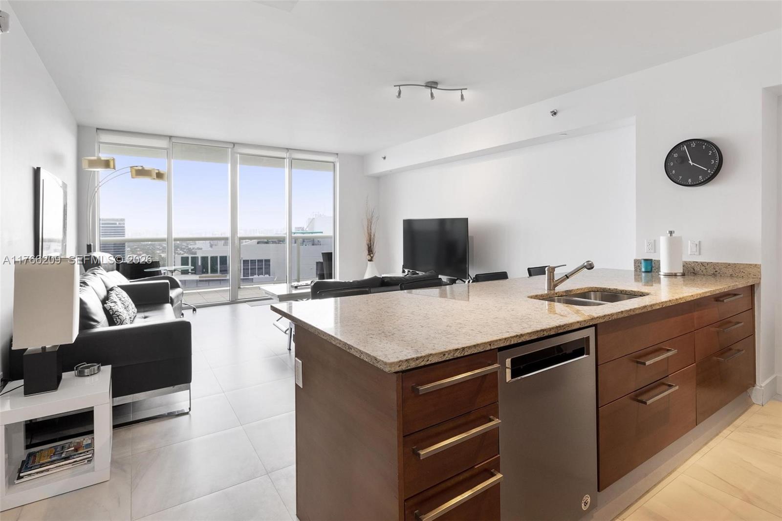 A modern kitchen island with granite countertops overlooks a living area with floor-to-ceiling windows — 1830 S OCEAN DR # 4705, Hallandale Beach FL 33009, HALLANDALE BEACH, FL