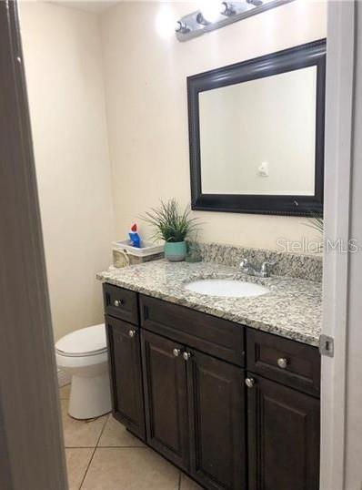 A bathroom features a dark wood vanity with a granite countertop and a framed mirror — 3211 BREWSTER DRIVE, KISSIMMEE, FL