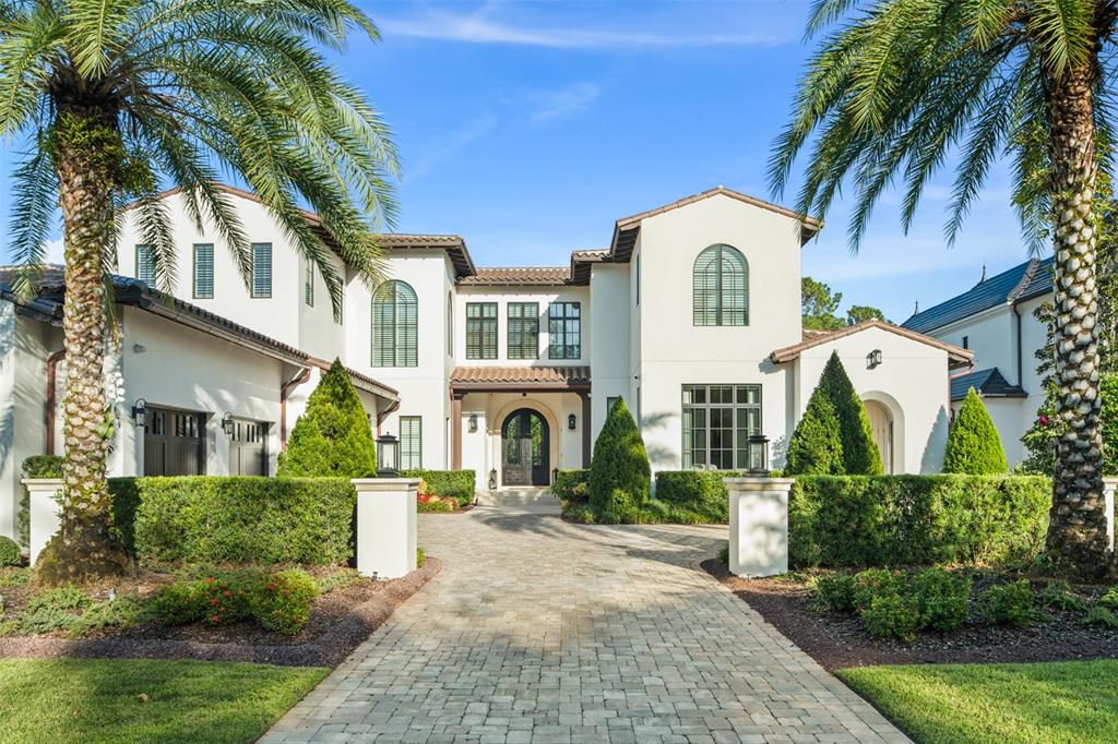 A two-story white stucco house with a paved driveway and palm trees in the front — 10331 LOS FELIZ DRIVE, ORLANDO, FL