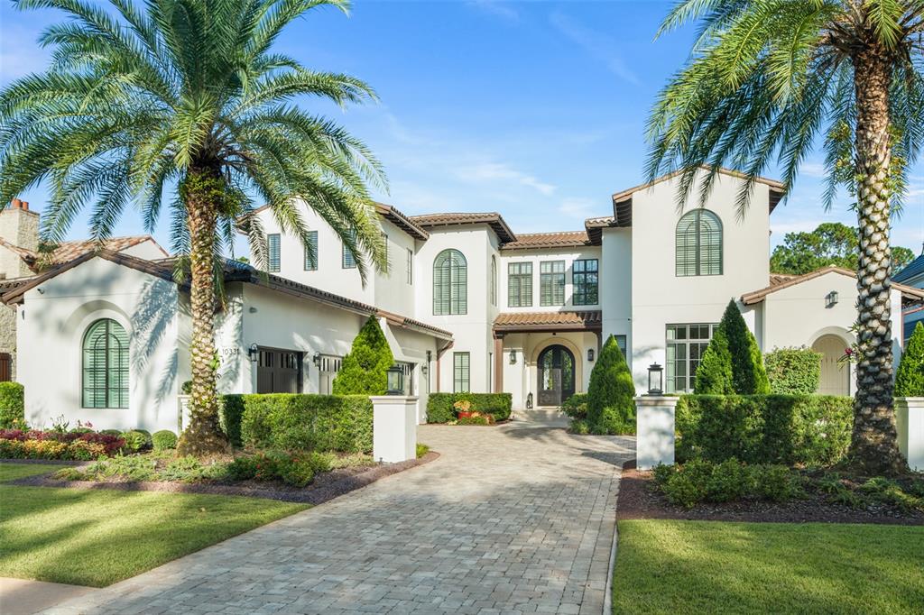 A two-story white stucco house with a paved driveway and palm trees in the front — 10331 LOS FELIZ DRIVE, ORLANDO, FL