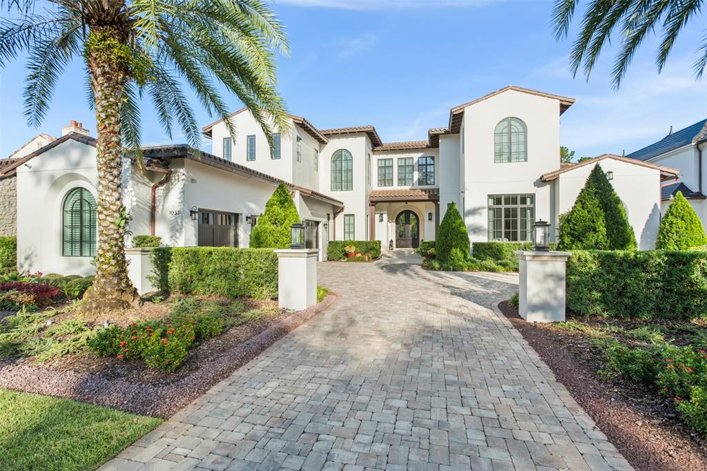 A two-story stucco house features a paved driveway, arched windows, and a palm tree — 10331 LOS FELIZ DRIVE, ORLANDO, FL