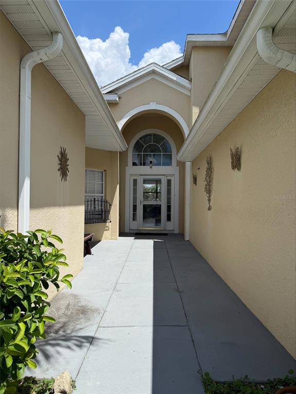 A concrete walkway leads to the arched entryway of a beige stucco house — 3511 MAPLE RIDGE LOOP, KISSIMMEE, FL