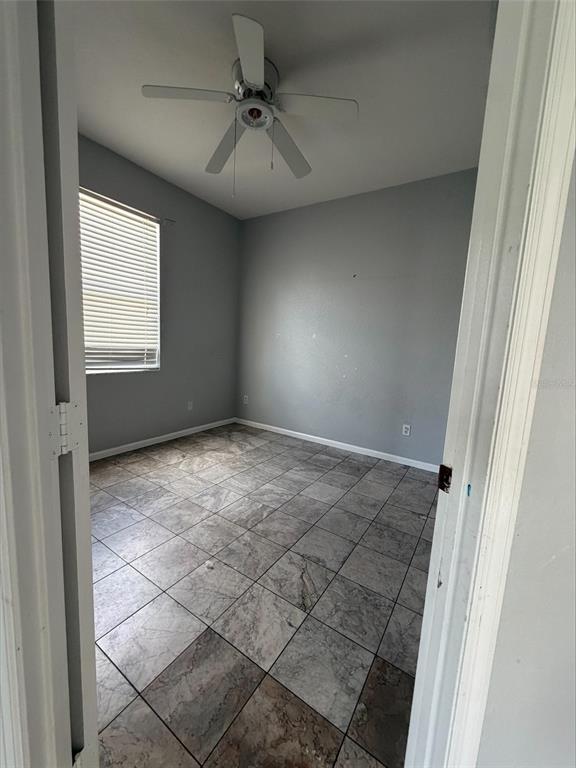 An empty bedroom with gray walls, a ceiling fan, and light-colored tile flooring — 3511 MAPLE RIDGE LOOP, KISSIMMEE, FL