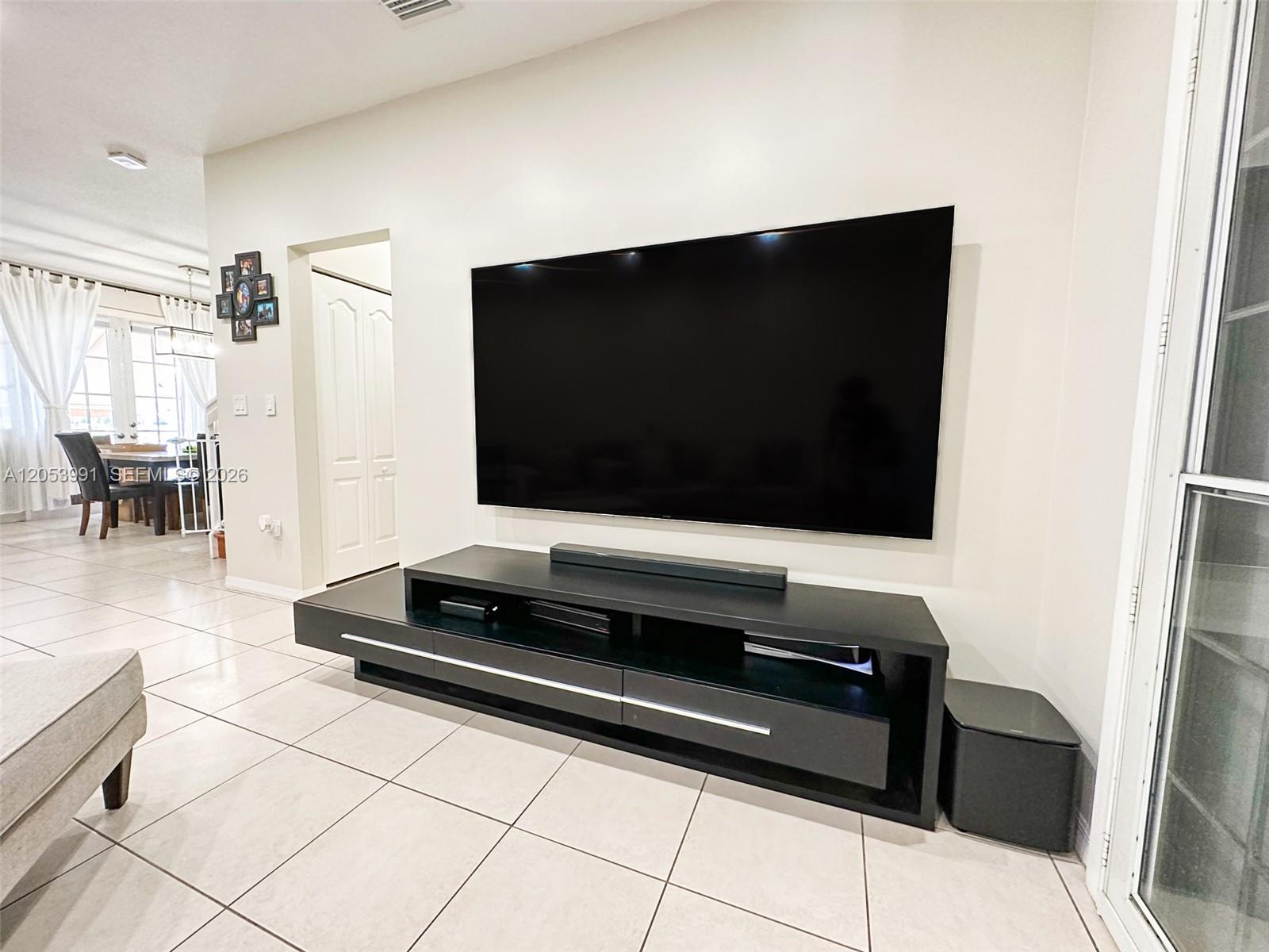 A living room features a large wall-mounted television above a black media console — 130 Riverwalk Cir # 130, Sunrise FL 33326, SUNRISE, FL