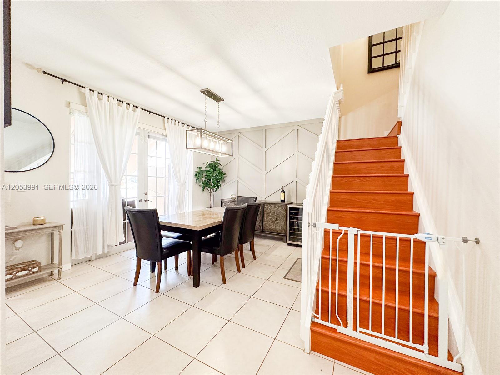 A dining room features a wooden staircase with a safety gate and tile flooring — 130 Riverwalk Cir # 130, Sunrise FL 33326, SUNRISE, FL
