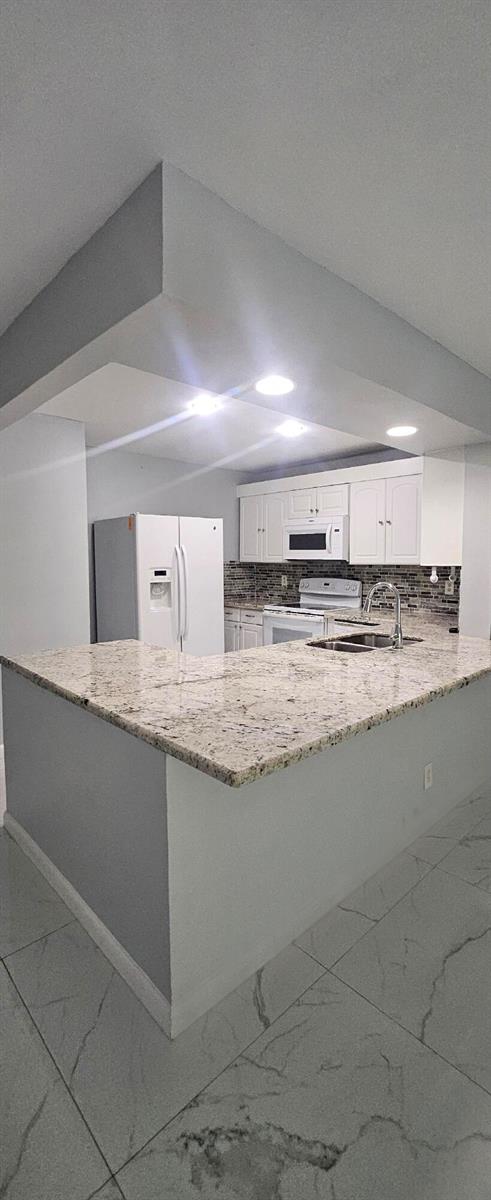 A kitchen features white cabinets, granite countertops, a white refrigerator, and light-colored tile flooring — 22465 SW 61st Way E # 247, Boca Raton FL 33428, BOCA RATON, FL