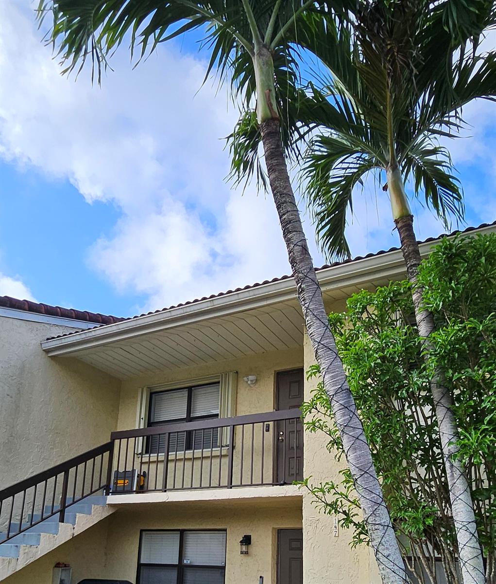 Exterior view of a two-story building with a balcony, stairs, and palm trees — 22465 SW 61st Way E # 247, Boca Raton FL 33428, BOCA RATON, FL