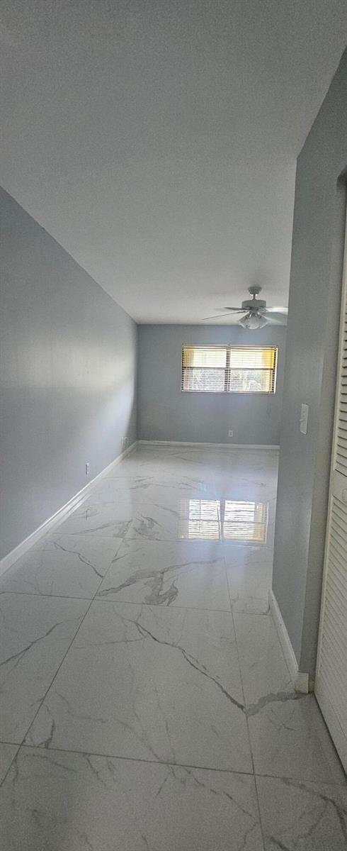 An empty room features light gray walls, white marble-look tile flooring, and a ceiling fan — 22465 SW 61st Way E # 247, Boca Raton FL 33428, BOCA RATON, FL