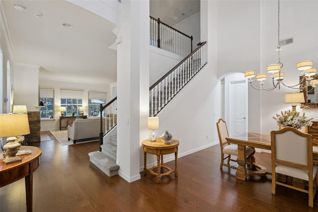 A bright foyer features hardwood floors, a staircase with white railings, and a dining area — 7773 MINUTEMEN LOOP, WINTER GARDEN, FL