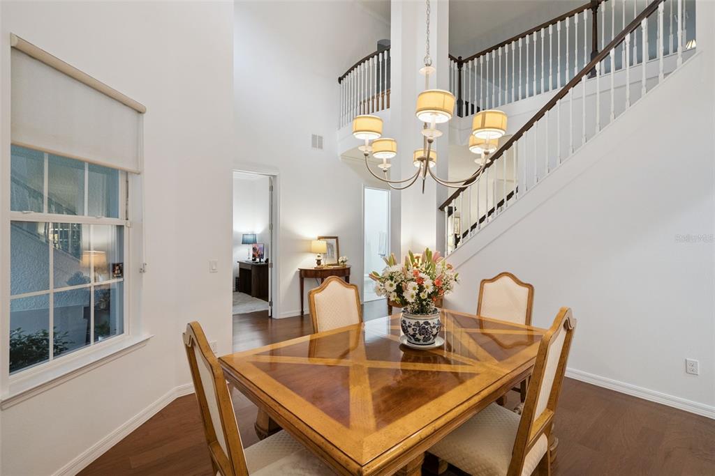 A dining room with a wooden table, chandelier, and staircase leading to a second-floor landing — 7773 MINUTEMEN LOOP, WINTER GARDEN, FL