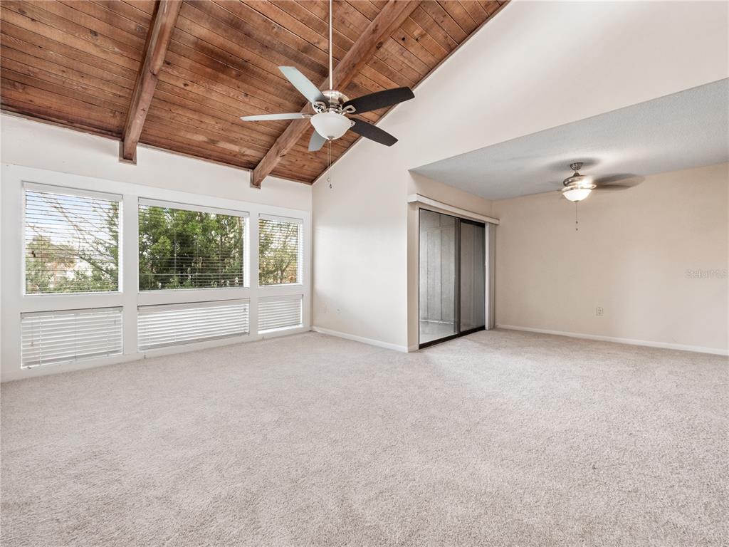 A living room features a vaulted wood-plank ceiling, carpeted flooring, and large windows — 5789 PEREGRINE AVENUE UNIT 30-C10-2, ORLANDO, FL
