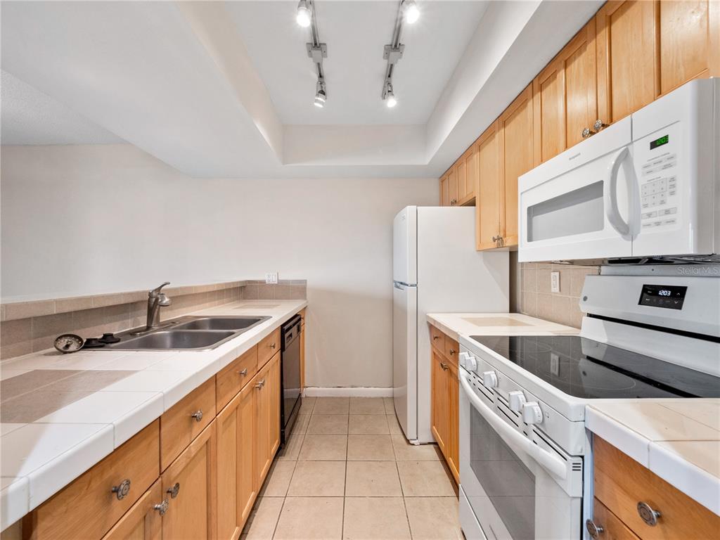 A kitchen features light wood cabinets, white tile countertops, and white appliances — 5789 PEREGRINE AVENUE UNIT 30-C10-2, ORLANDO, FL