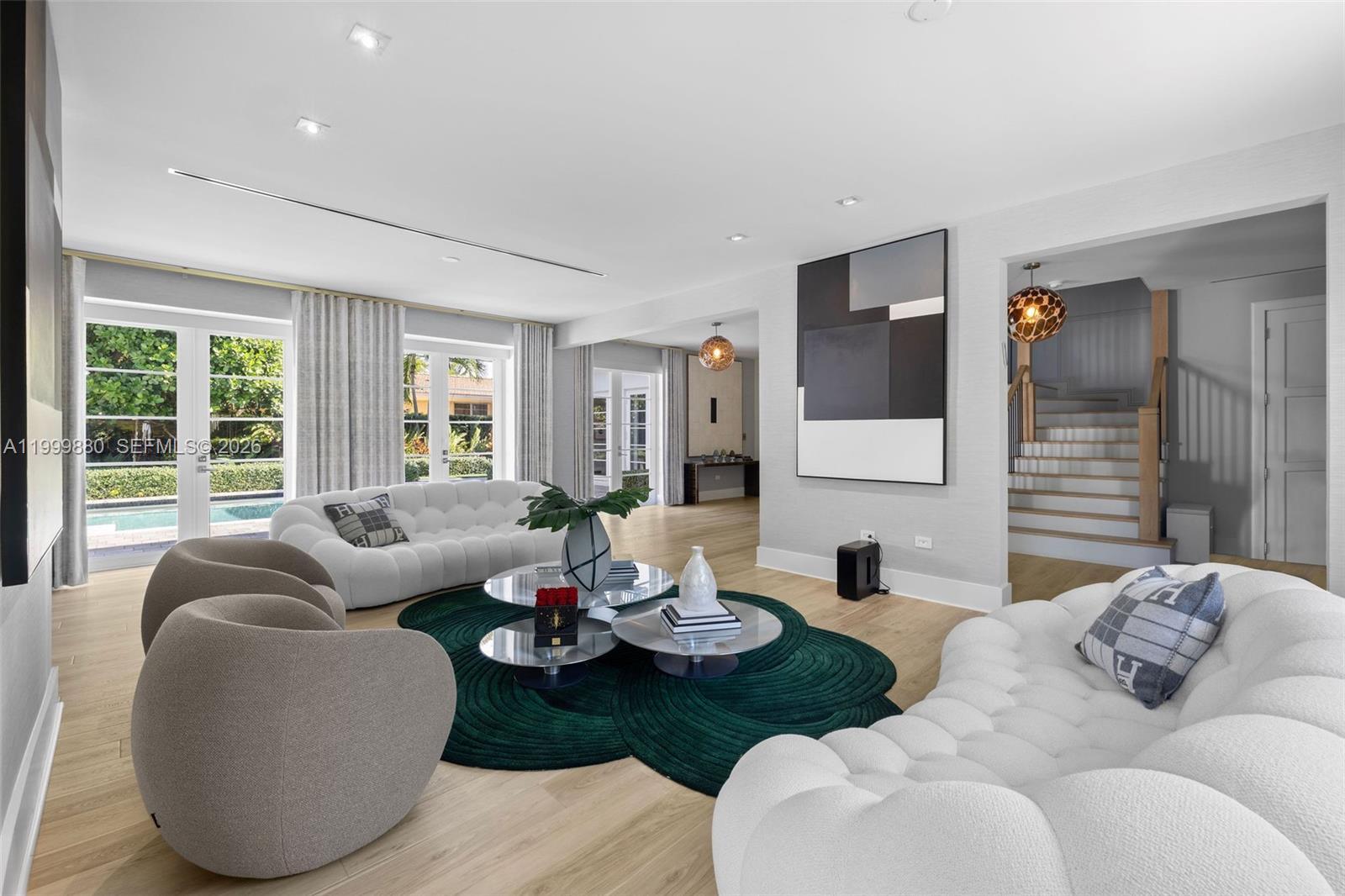 A bright living room features two white tufted sofas, round coffee tables, and a green rug — 2887 Pine Tree Dr, Miami Beach FL 33140, MIAMI BEACH, FL