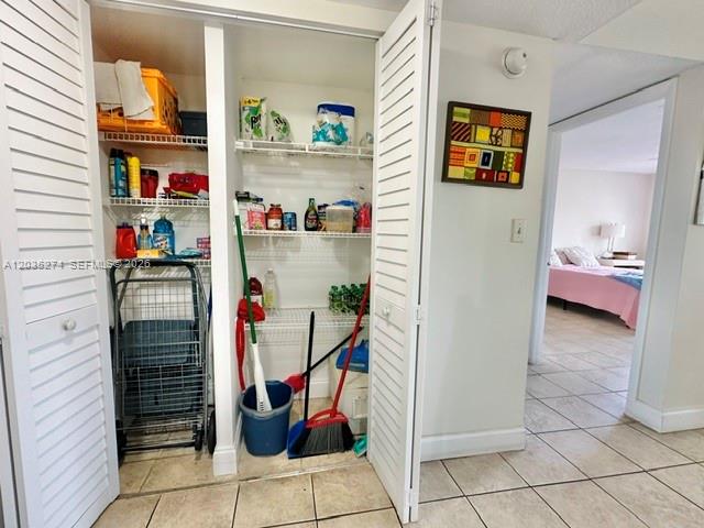 A white louvered closet with shelves and cleaning supplies stands beside a doorway to a bedroom — 9301 SW 92nd Ave # A407, Miami FL 33176, MIAMI, FL