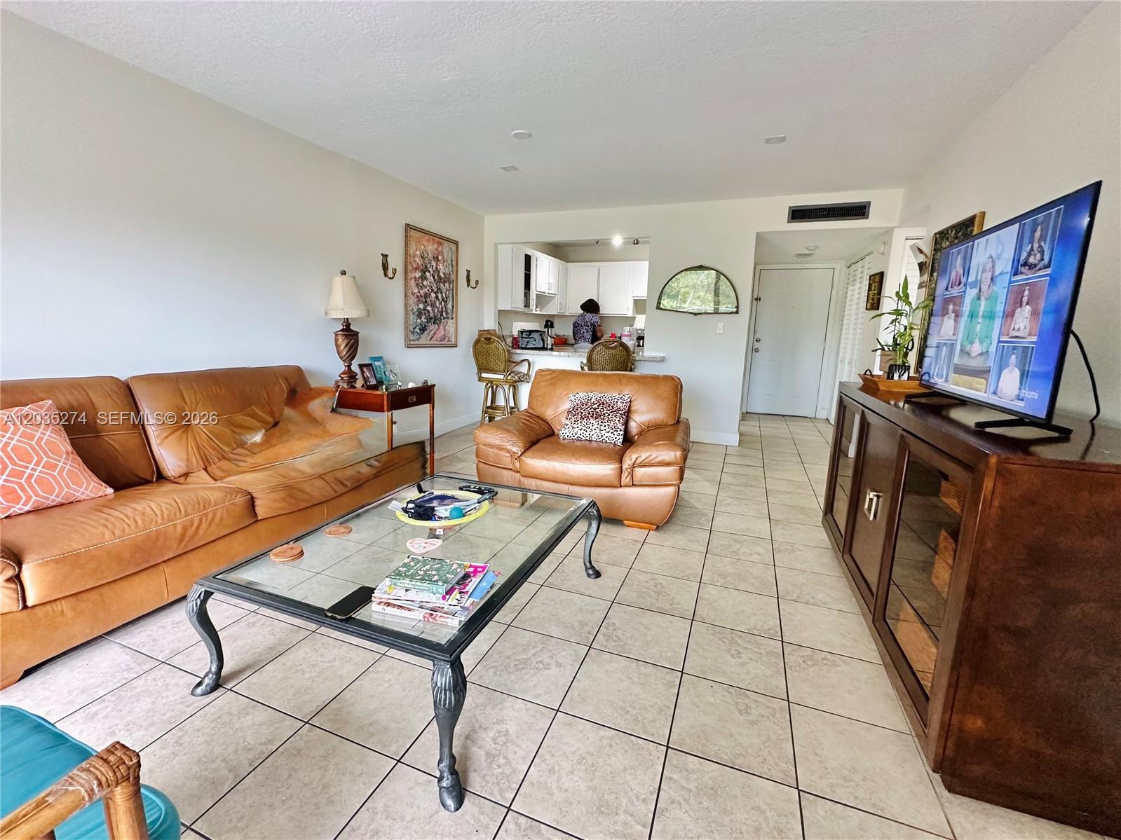 A living room features tan leather furniture, a glass coffee table, and tile flooring — 9301 SW 92nd Ave # A407, Miami FL 33176, MIAMI, FL
