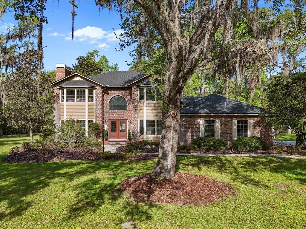 A two-story brick and siding house with a large tree in the front yard — 1118 SW 112TH STREET, GAINESVILLE, FL