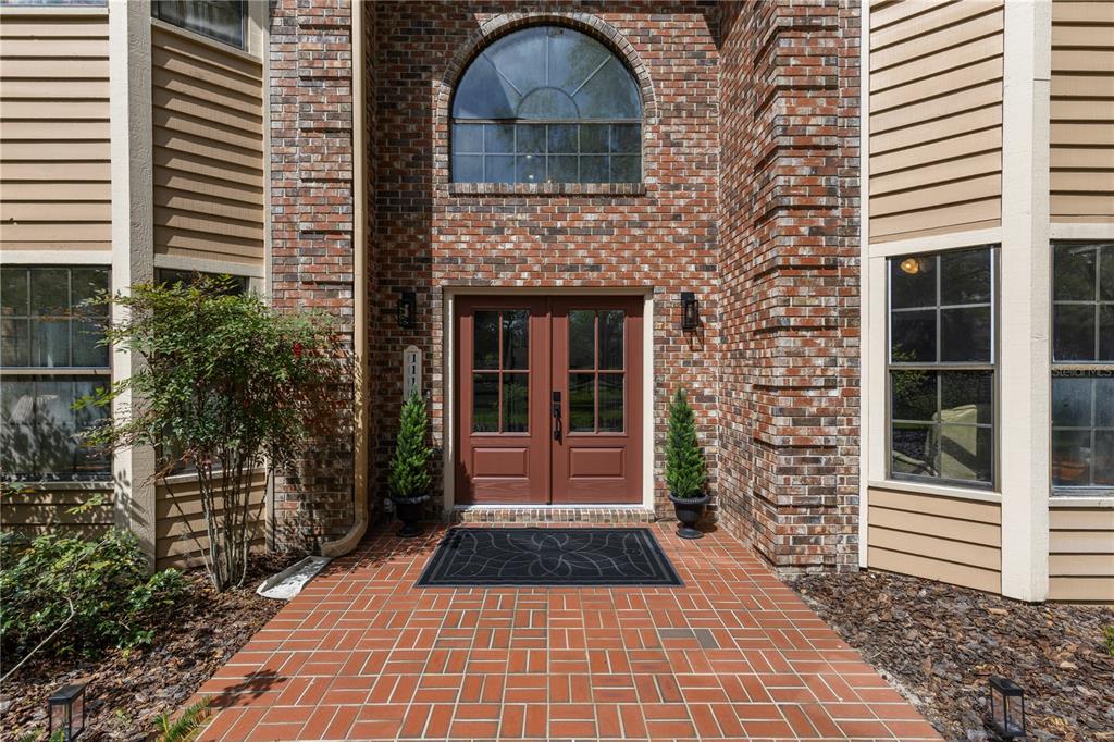A brick entryway features double doors, a large arched window, and a herringbone-patterned brick walkway — 1118 SW 112TH STREET, GAINESVILLE, FL