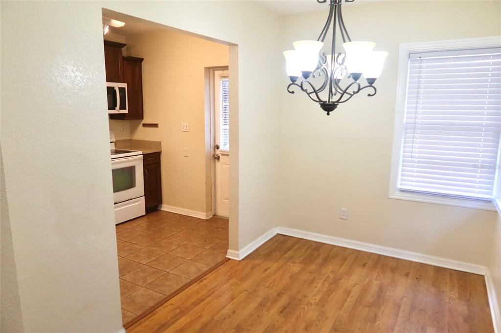 A dining area with wood-look flooring and a chandelier opens into a tiled kitchen — 2704 NW 1ST AVENUE, GAINESVILLE, FL