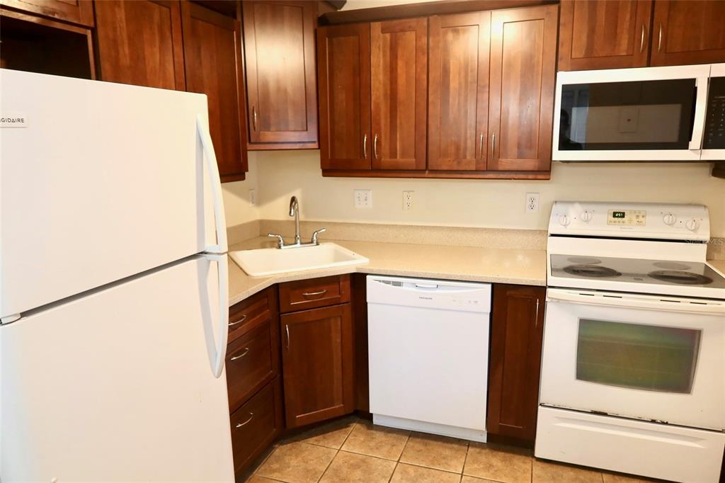 A kitchen with white appliances, wooden cabinets, and light-colored countertops — 2704 NW 1ST AVENUE, GAINESVILLE, FL