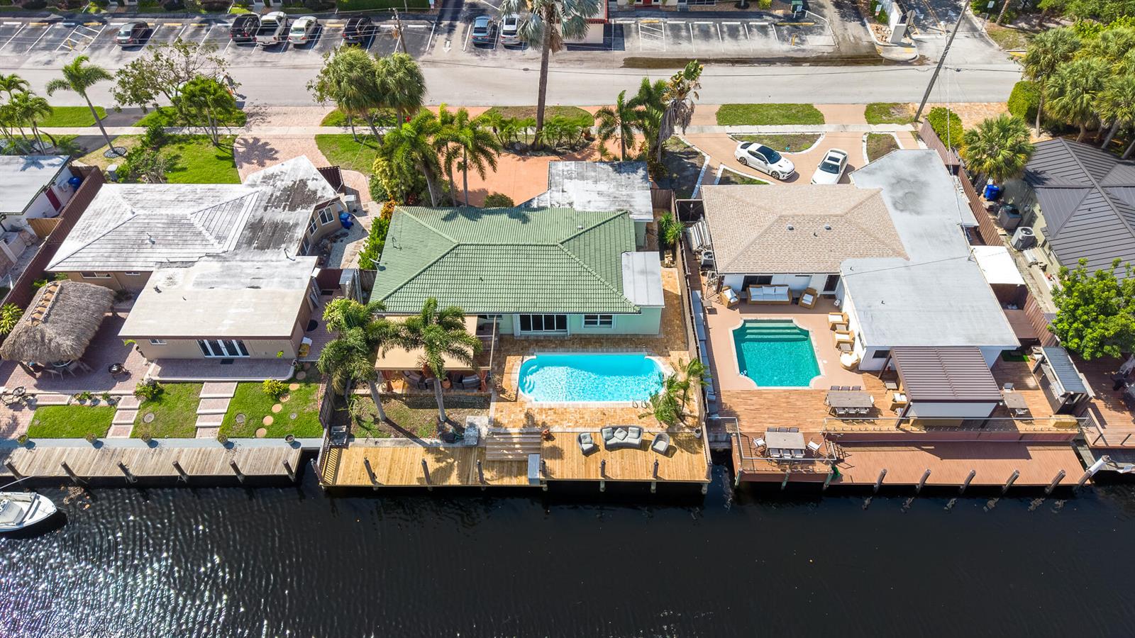 Aerial view of three waterfront houses with swimming pools and wooden docks along a canal — 101 SE 14th Street, Pompano Beach FL 33060, POMPANO BEACH, FL