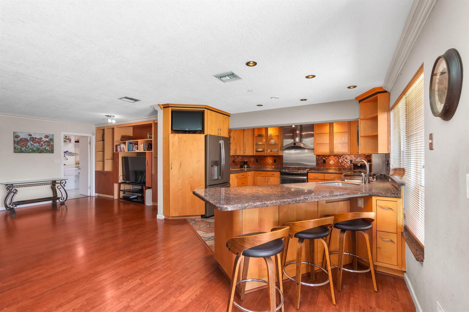 A kitchen with wood cabinets, granite countertops, and a breakfast bar with three stools — 101 SE 14th Street, Pompano Beach FL 33060, POMPANO BEACH, FL