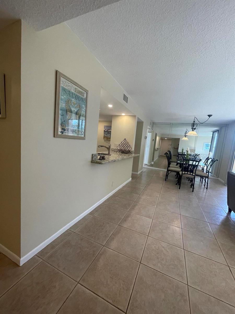 A tiled hallway leads to a dining area with mirrored walls and a kitchen pass-through — 450 Egret Circle # 9203, Delray Beach FL 33444, DELRAY BEACH, FL