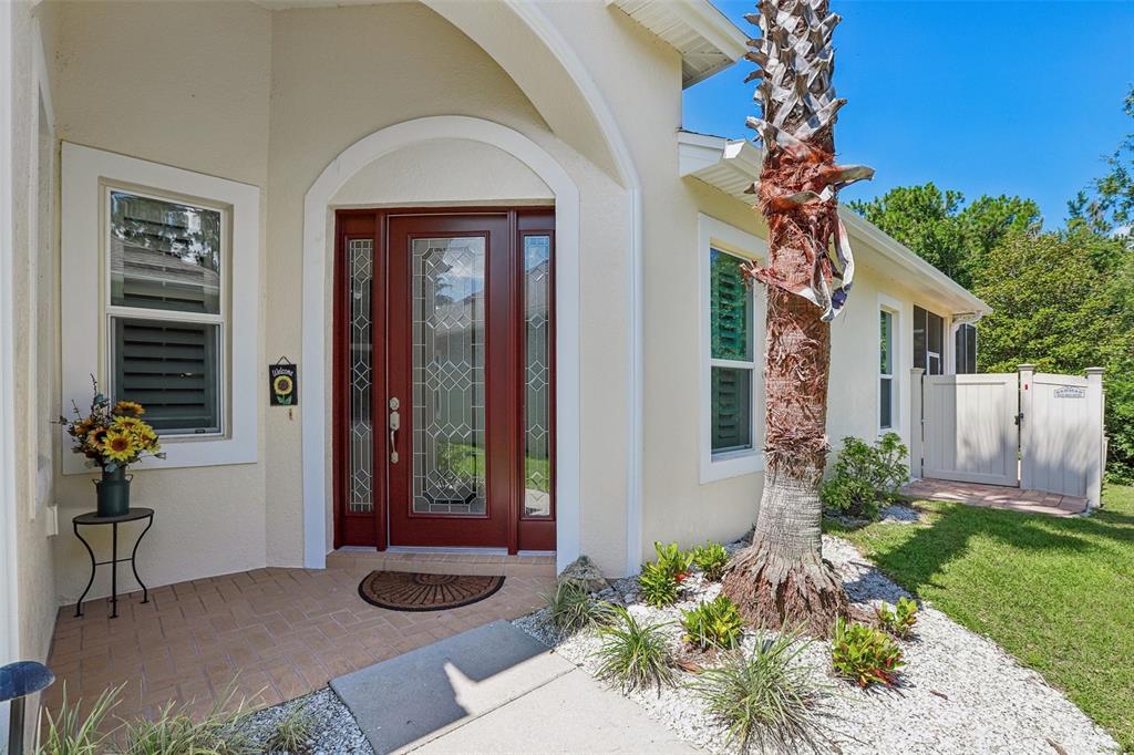 A front entryway features a red door with glass panels, a palm tree, and landscaping — 2849 DEVONOAK BOULEVARD, LAND O LAKES, FL