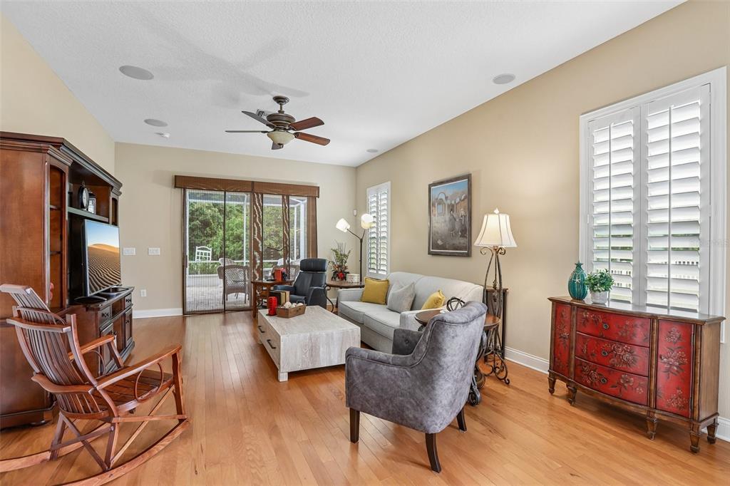 A living room features hardwood floors, a ceiling fan, a sofa, and a red cabinet — 2849 DEVONOAK BOULEVARD, LAND O LAKES, FL