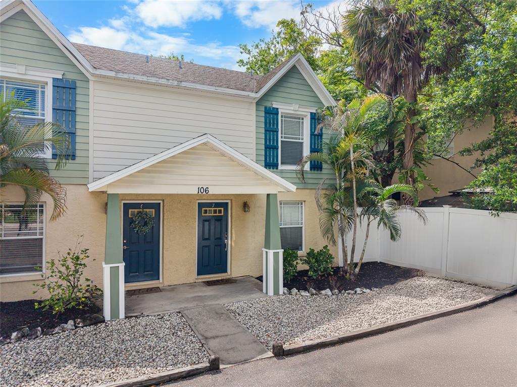 A two-story townhouse with light green siding, blue shutters, and a covered front porch — 106 S HABANA AVENUE UNIT 7, TAMPA, FL