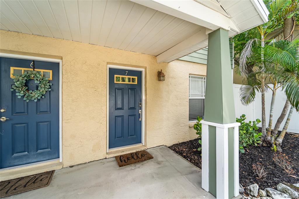 The exterior view shows two blue front doors with wreaths and welcome mats under a porch — 106 S HABANA AVENUE UNIT 7, TAMPA, FL