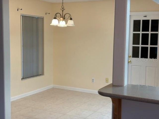 A dining area features tile flooring, a chandelier, a window with blinds, and a door — 1922 DOCKSIDE DRIVE, VALRICO, FL