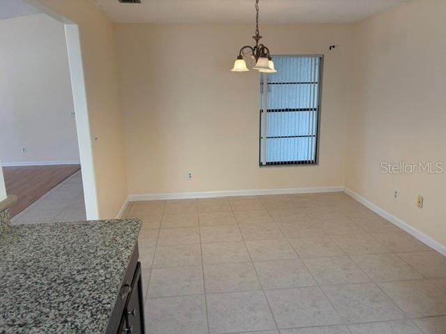 An empty dining area features light-colored floor tiles, a chandelier, and a window with blinds — 1922 DOCKSIDE DRIVE, VALRICO, FL