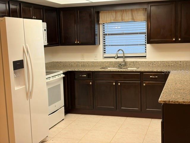 A kitchen features dark wood cabinets, granite countertops, a white refrigerator, and a window — 1922 DOCKSIDE DRIVE, VALRICO, FL