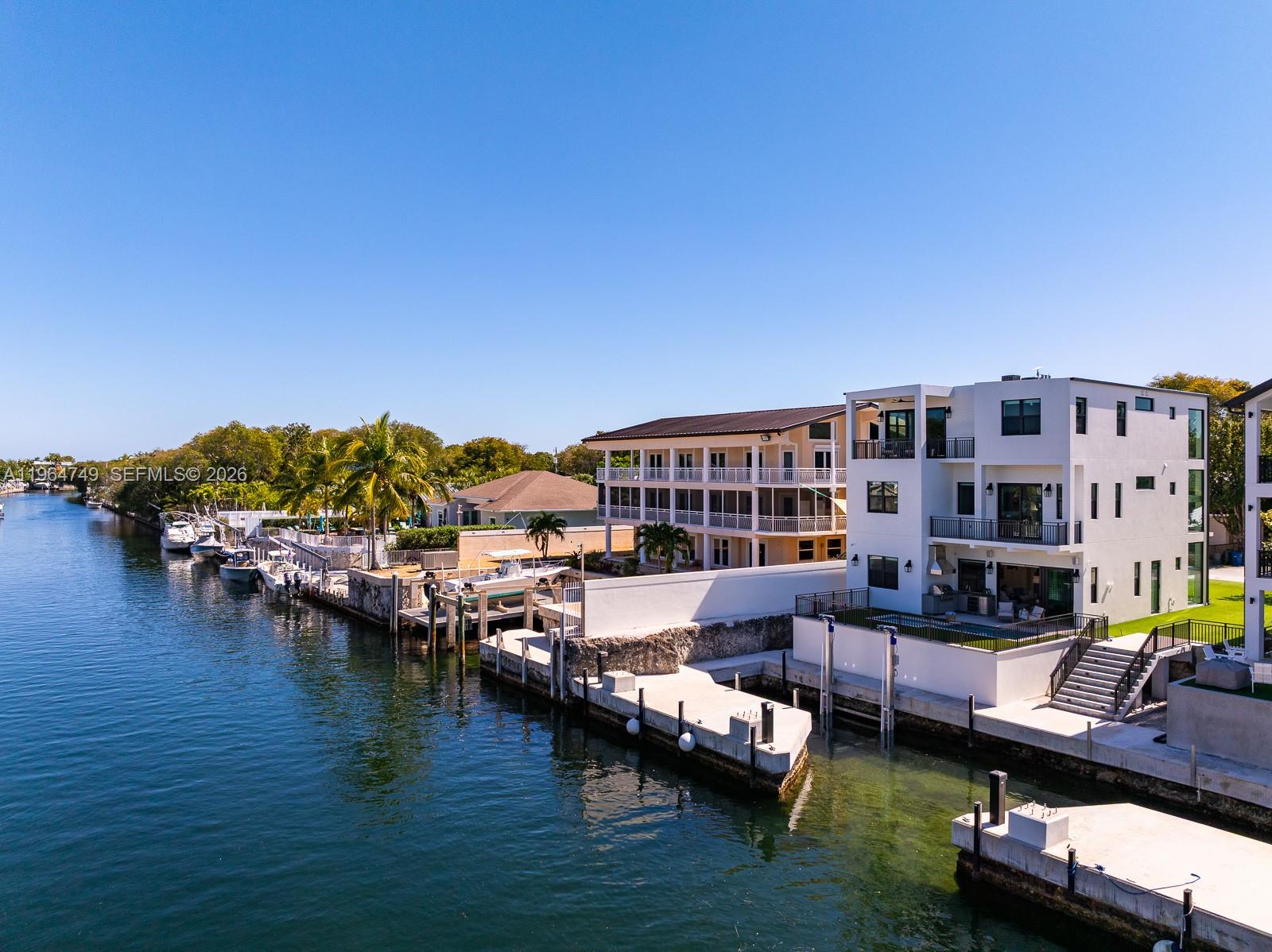 An aerial view shows a modern white house with a pool along a canal — 16 Bass Ave, Key Largo FL 33037, KEY LARGO, FL