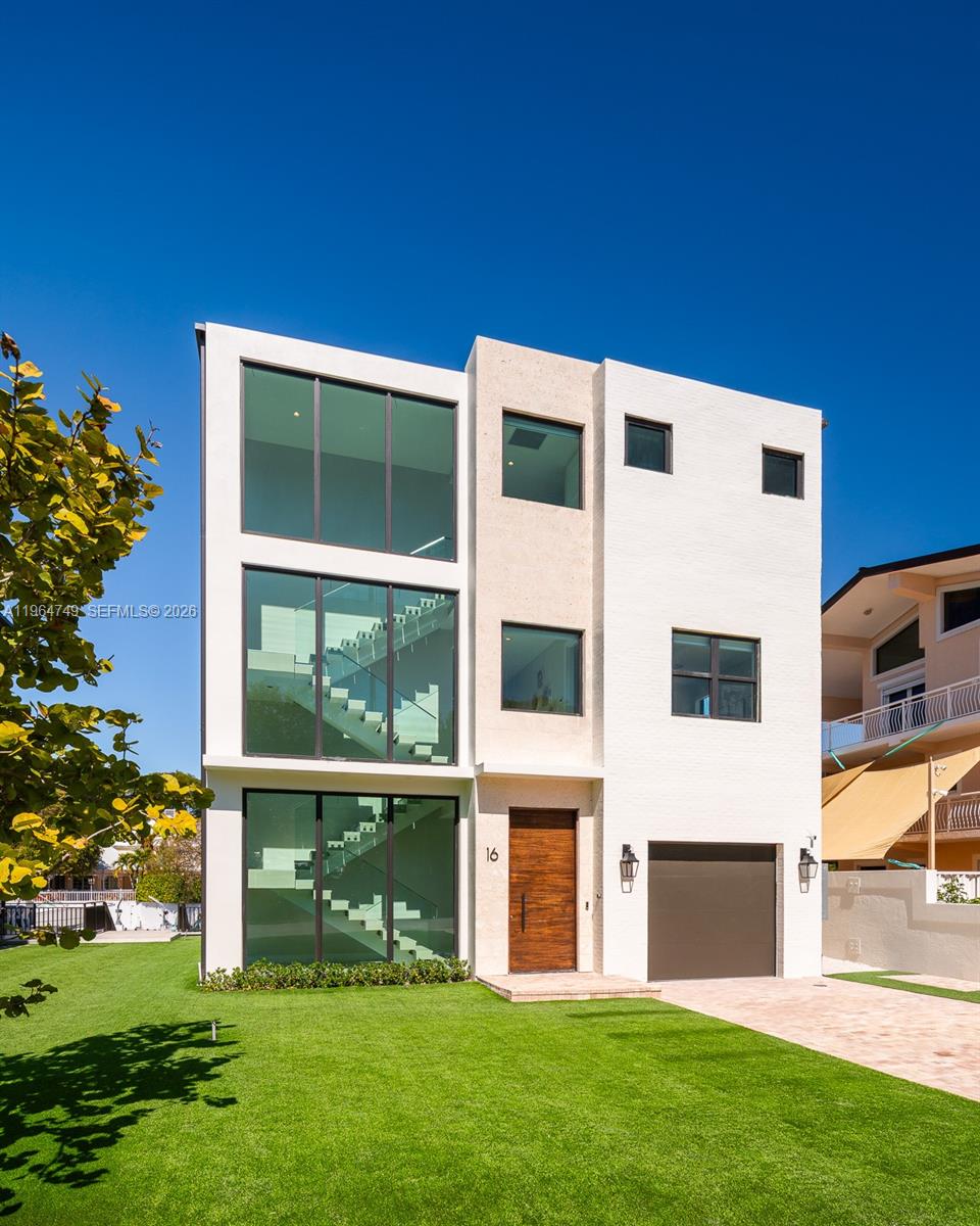 A three-story modern house with large glass windows, a wooden front door, and a garage — 16 Bass Ave, Key Largo FL 33037, KEY LARGO, FL