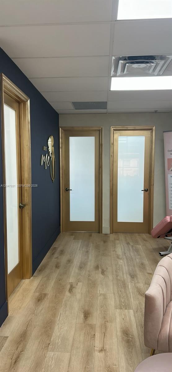 A hallway with light wood flooring, a dark blue accent wall, and three gold-framed doors — 1730 Main St # 210, Weston FL 33326, WESTON, FL