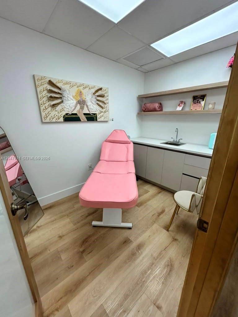 A treatment room features a pink massage table, light wood flooring, and a wall-mounted sink — 1730 Main St # 210, Weston FL 33326, WESTON, FL