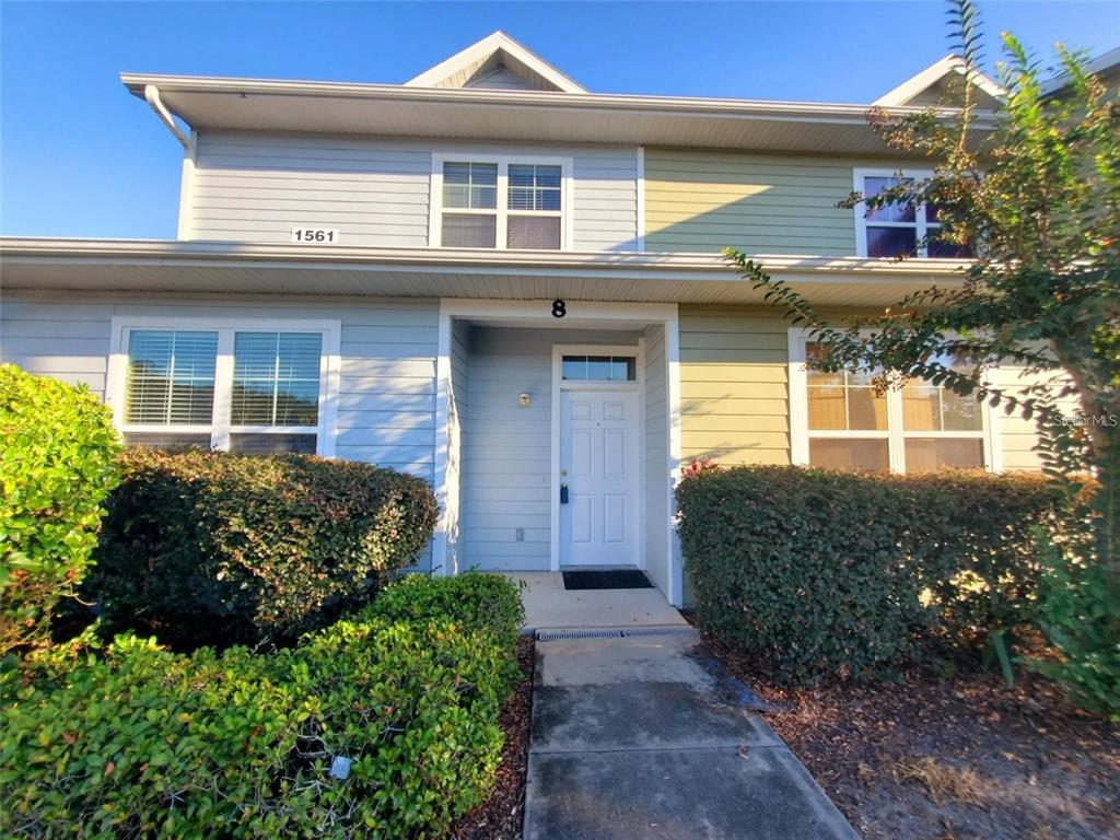 A two-story townhouse exterior with light blue and green siding and a white front door — 1561 NW 29TH ROAD UNIT 8, GAINESVILLE, FL
