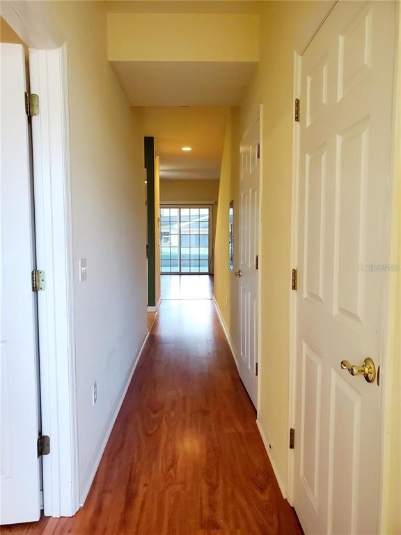 A hallway with wood-look flooring leads toward a glass sliding door at the end — 1561 NW 29TH ROAD UNIT 8, GAINESVILLE, FL