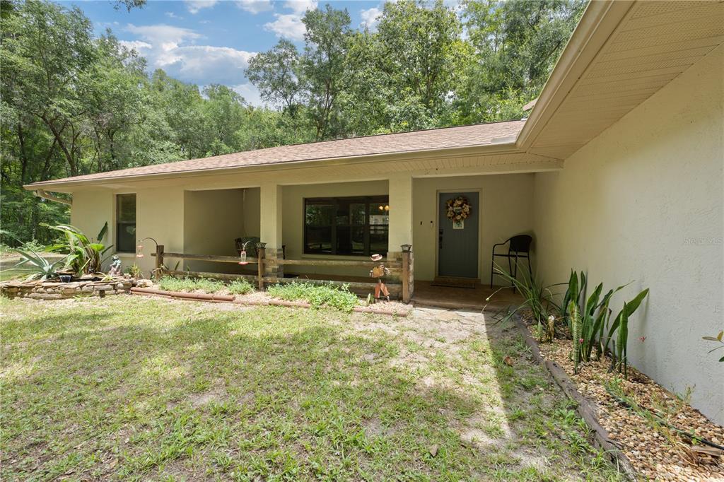 A single-story house exterior features a covered porch, a wooden fence, and a front door — 18451 NW 141ST AVENUE, WILLISTON, FL
