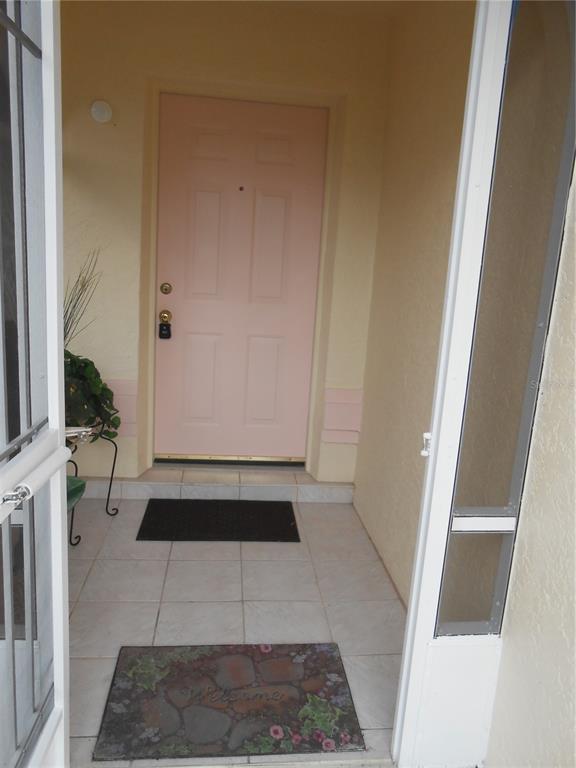 A light pink front door is framed by a tiled entryway and a screen door — 21239 GAYLORD AVENUE, PORT CHARLOTTE, FL