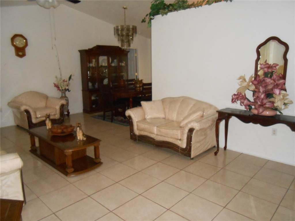 A living room with tile flooring, a beige sofa, an armchair, and a dining area — 21239 GAYLORD AVENUE, PORT CHARLOTTE, FL