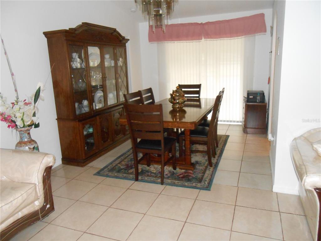 A dining room features a wooden hutch, a table with six chairs, and tile flooring — 21239 GAYLORD AVENUE, PORT CHARLOTTE, FL