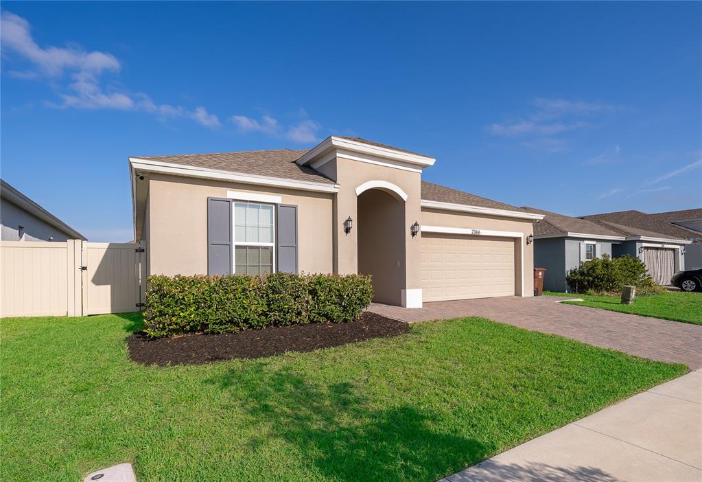 A single-story house with a beige stucco exterior, a two-car garage, and a front lawn — 2366 WHITE CEDAR WAY, HAINES CITY, FL