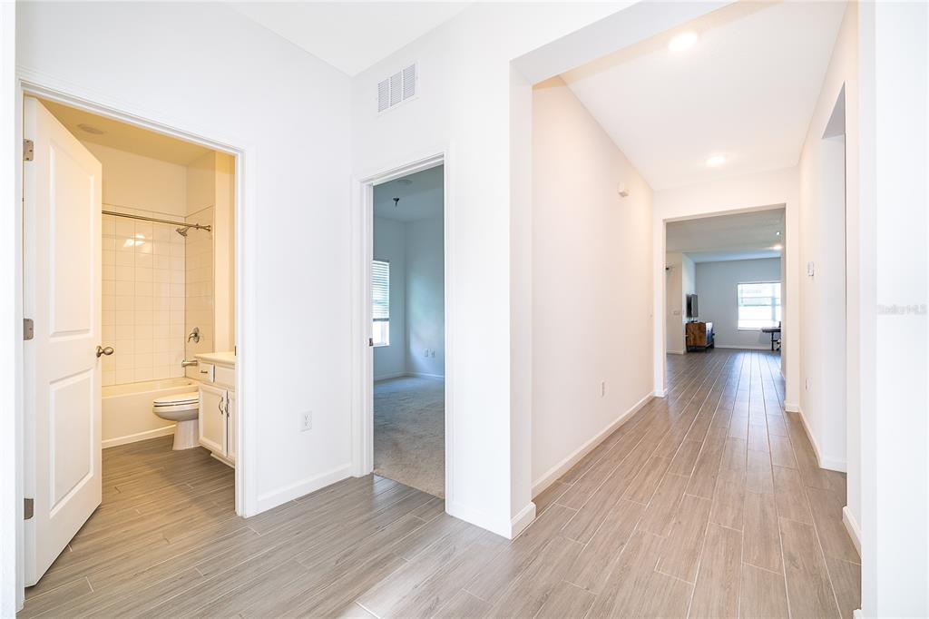 A hallway with wood-look tile flooring leads to a bathroom, a bedroom, and a living area — 2366 WHITE CEDAR WAY, HAINES CITY, FL