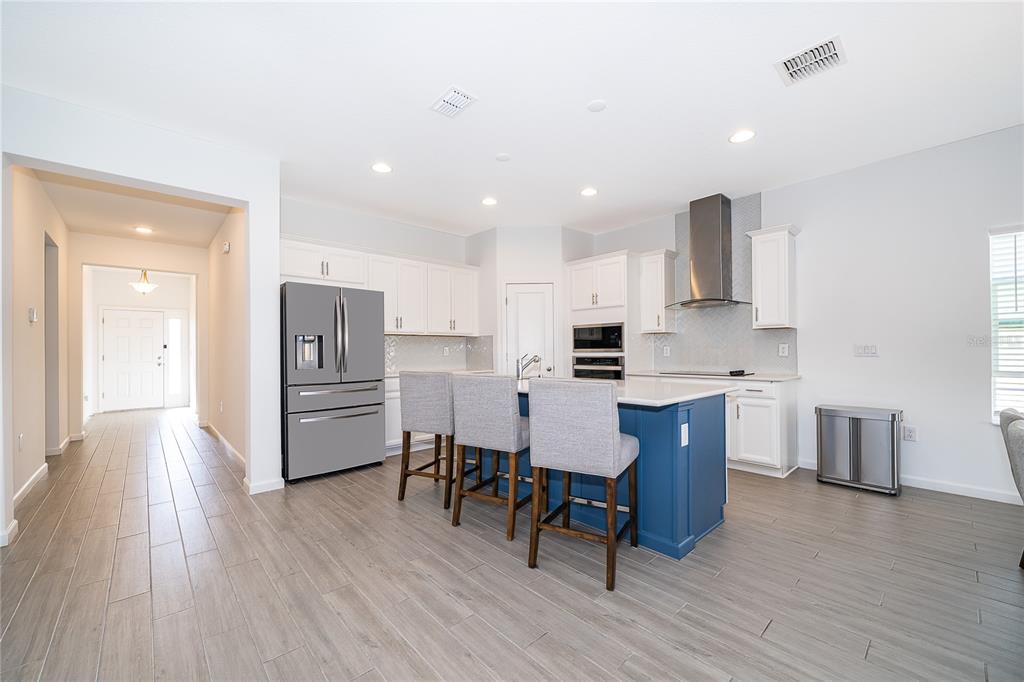 A kitchen features a blue island with bar stools, white cabinetry, and stainless steel appliances — 2366 WHITE CEDAR WAY, HAINES CITY, FL