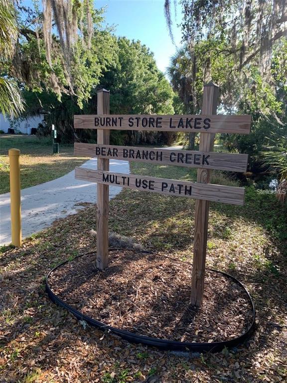 A wooden sign for Burnt Store Lakes Bear Branch Creek Multi Use Path stands outdoors — 16178 TRADING POST ROAD, PUNTA GORDA, FL