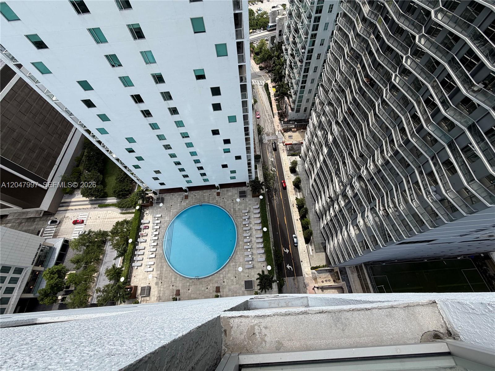 An elevated view shows a circular swimming pool between two tall apartment buildings — 500 Brickell Ave # 2907, Miami FL 33131, MIAMI, FL
